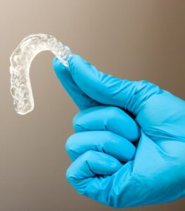 Imagen de un odontólogo mostrando un protector bucal para el tratamiento del bruxismo