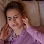 Imagen destacada de un post de blog sobre el bruxismo y sus consecuencias en la salud bucal. La imagen muestra una persona despertando con dolor en la mandíbula y los dientes sintiendolos apretados y desgastados.